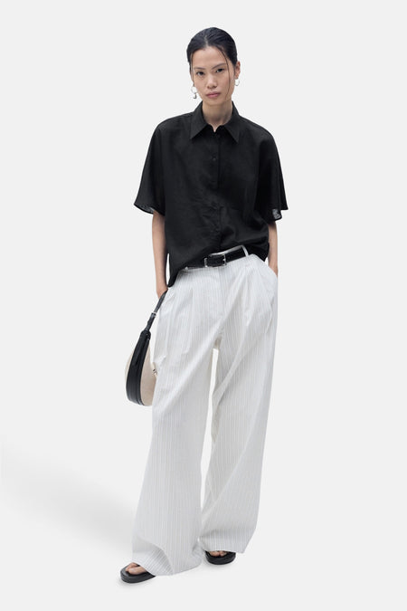 Zwart overhemd met korte mouwen van MANGO, gedragen met een gestreepte broek en een zwarte riem.
