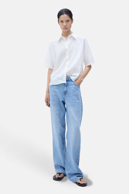 Wit blouse met korte mouwen van MANGO, gedragen met een wijde spijkerbroek en zwarte sandalen.