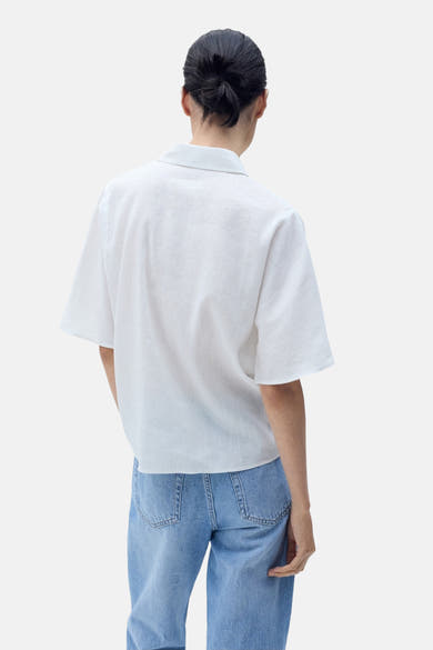 Witte blouse met korte mouwen van MANGO, rugdetail, gedragen met een lichtblauwe jeans.