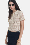 Beige ronde hals trui van MANGO, met ajourpatroon, gedragen met een donkere rok en een zonnebril.
