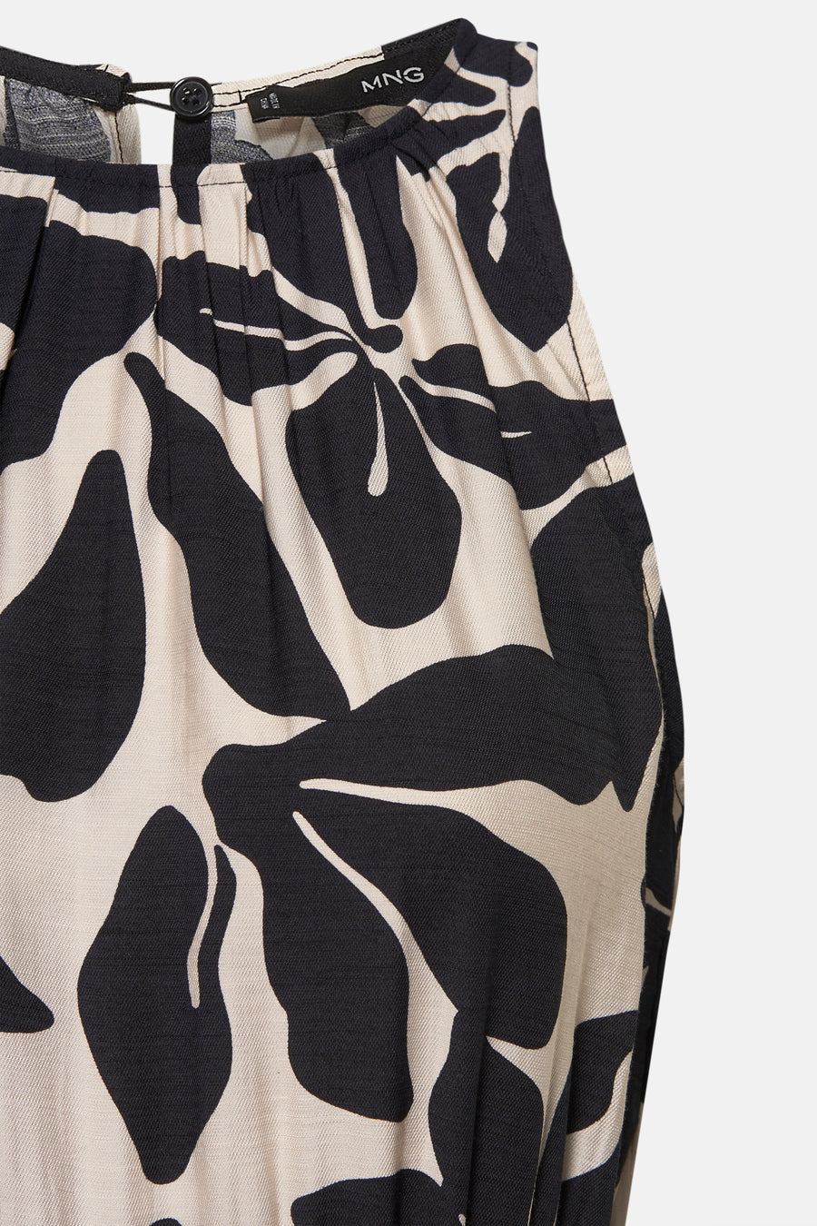 Combinaison noire à motif floral de MANGO, avec un bouton et des plis à l'encolure.
