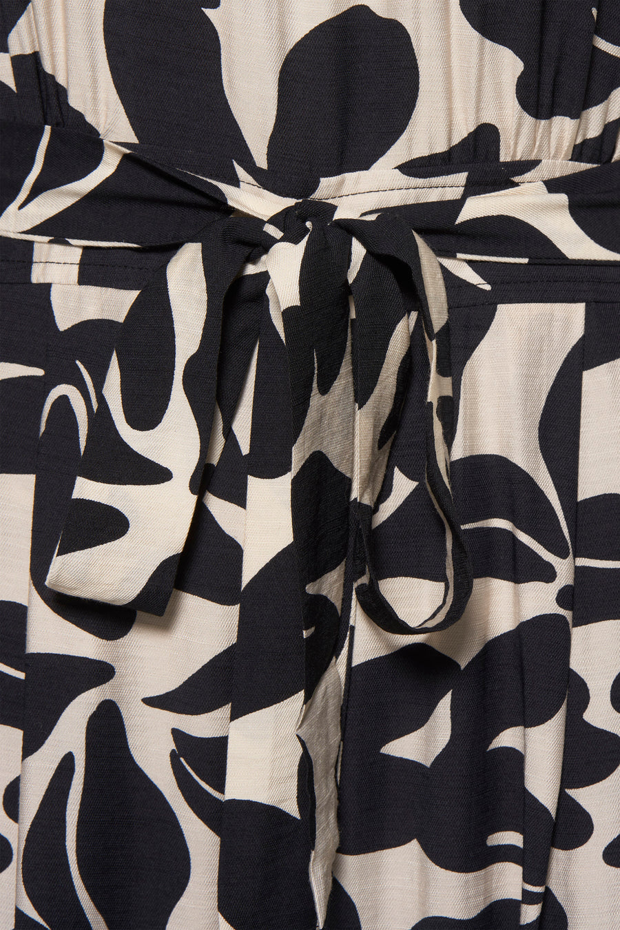 Combinaison noire de MANGO avec motif floral contrastant, ceinture nouée à la taille.
