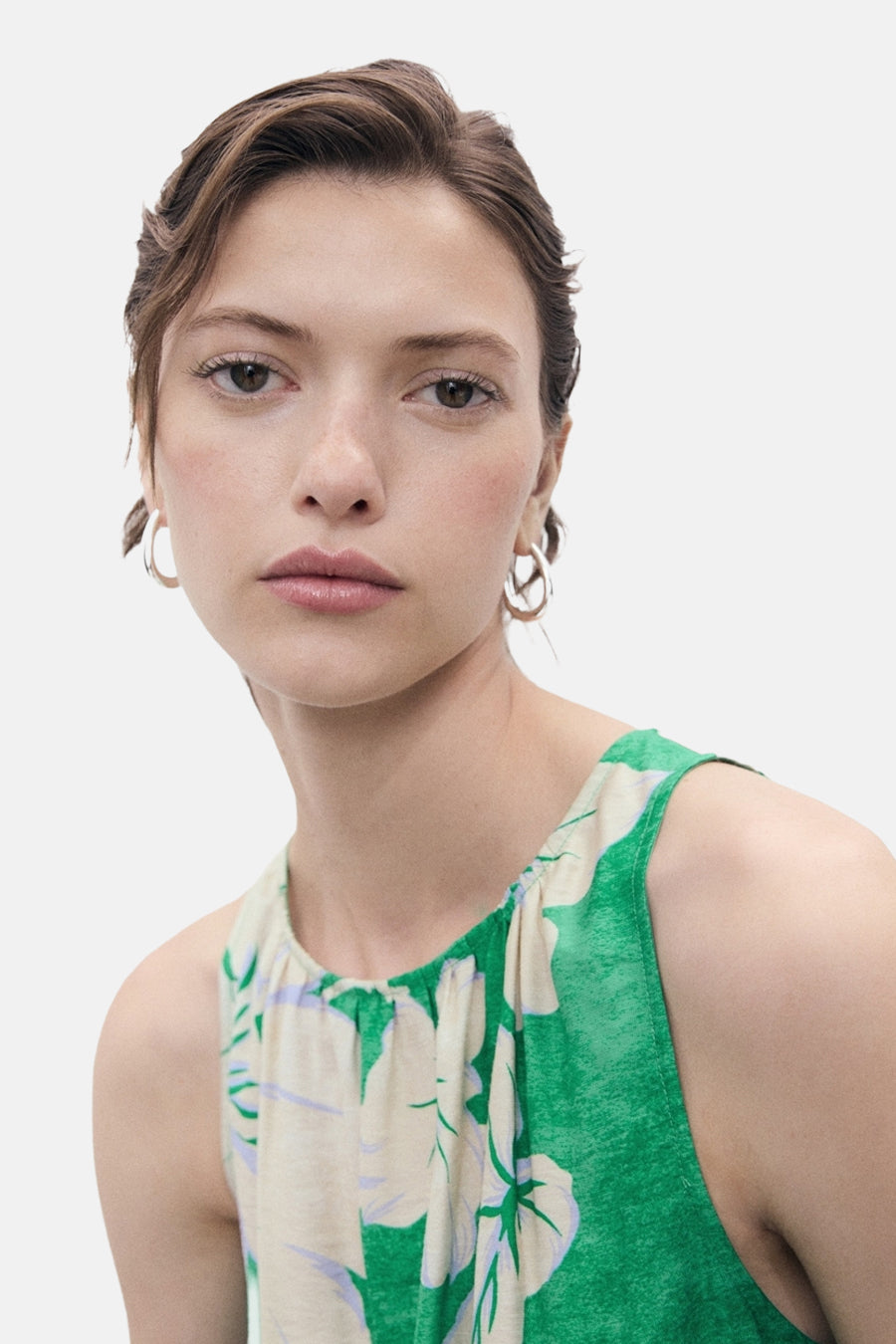 Groen MANGO-pak met bloemenprint, gedragen met zilveren oorbellen.