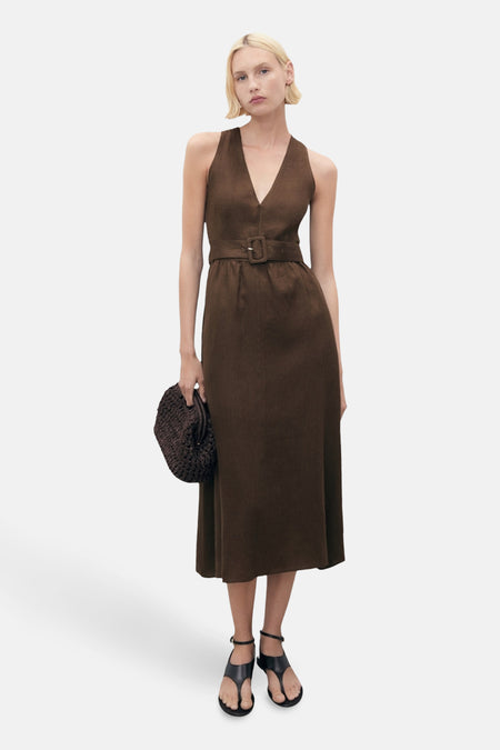 Robe marron ceinturée par MANGO, coupe midi, avec encolure en V et une personne portant des sandales et tenant un sac à main.