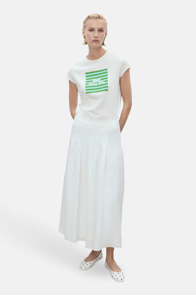 Wit T-shirt met korte mouwen van MANGO met een groen gestreept patroon op de voorkant, gedragen met een witte rok.