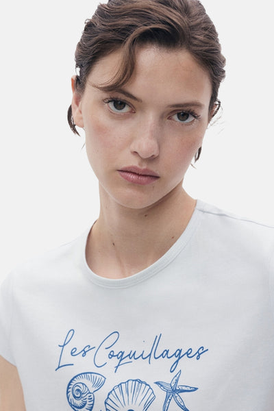 T-shirt à manches courtes bleu, de MANGO, avec un imprimé de coquillages bleus sur le devant.