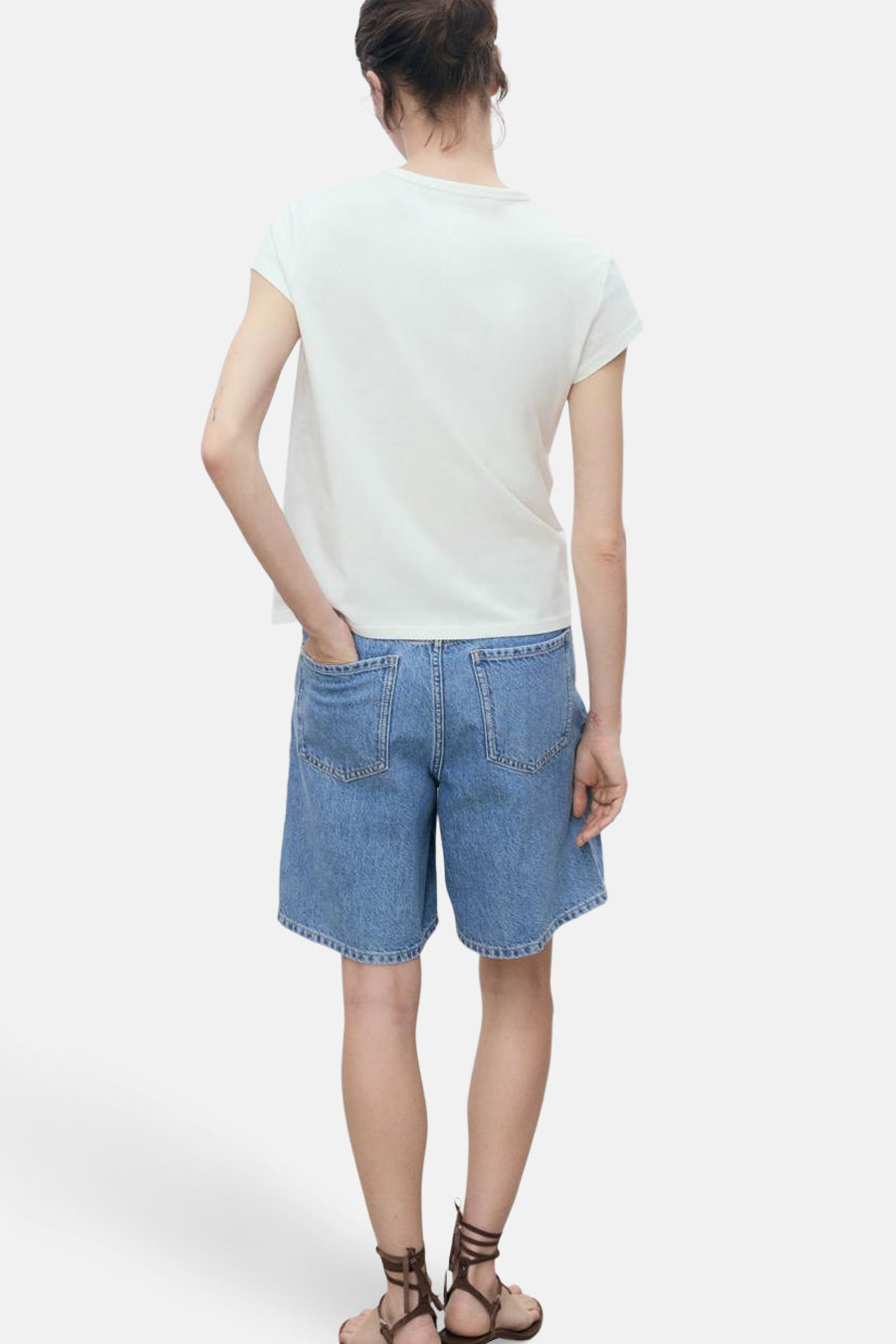 Wit T-shirt met korte mouwen van MANGO, gedragen met een spijkerbroekshort en leren sandalen met bandjes, achterzijde.