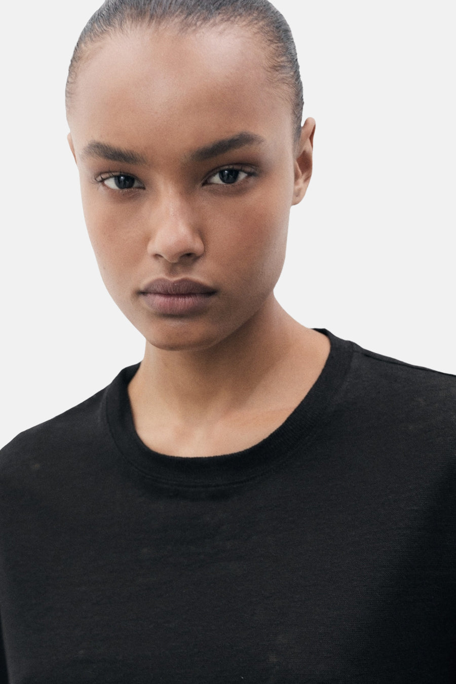 Zwart T-shirt met korte mouwen van MANGO, gedragen door een model met een neutrale achtergrond.
