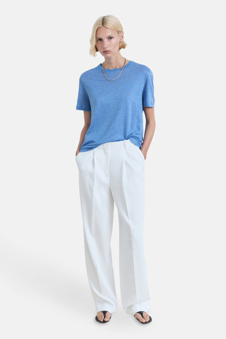 Blauw T-shirt met korte mouwen van MANGO, gedragen met een witte broek en zwarte sandalen.