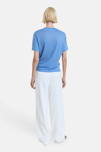 Blauwe T-shirt met korte mouwen van MANGO, gedragen met een wijde witte broek, achtergezicht.