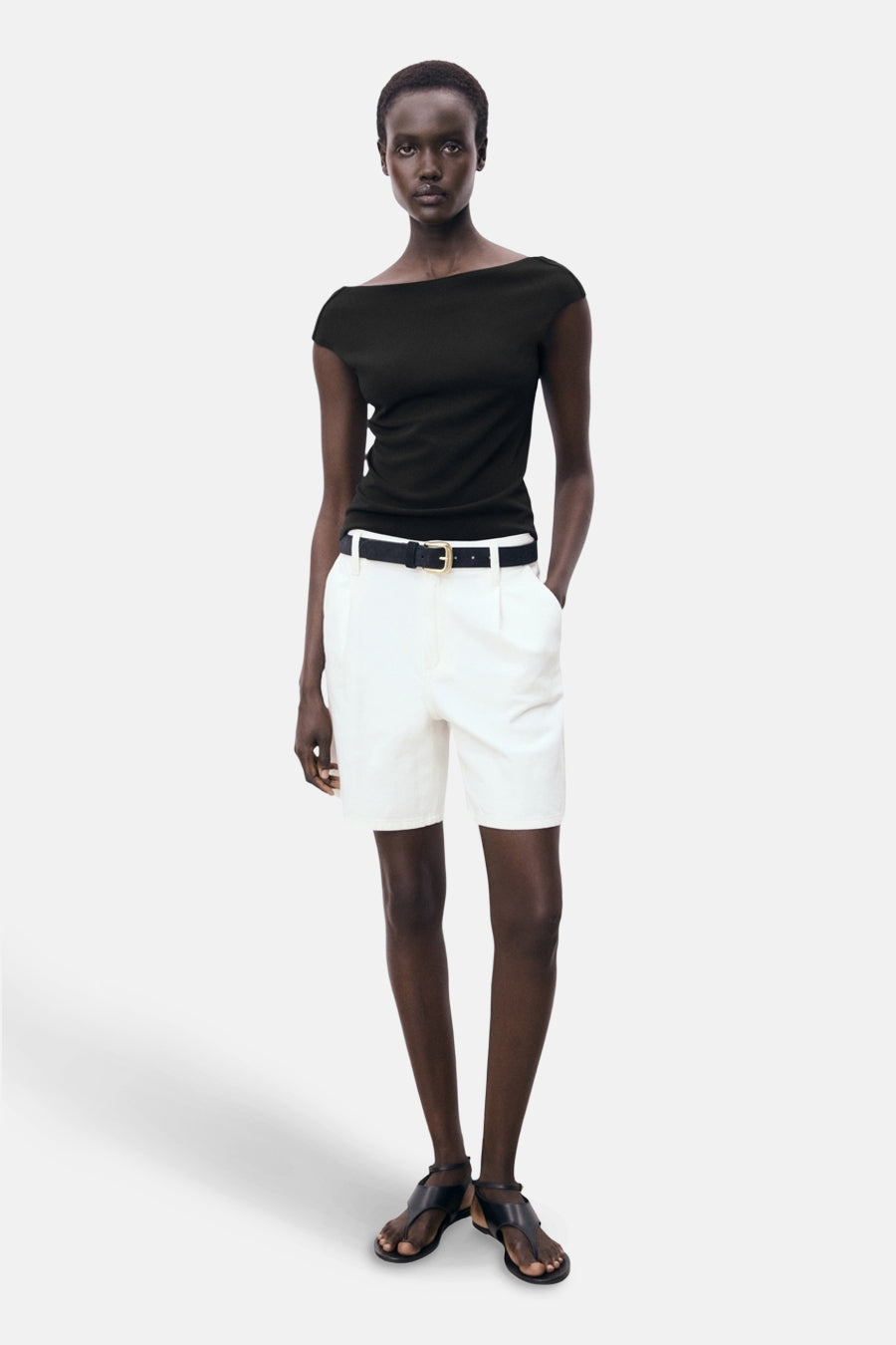 Zwart T-shirt met korte mouwen van MANGO, gedragen met een witte short met hoge taille en een zwarte riem.
