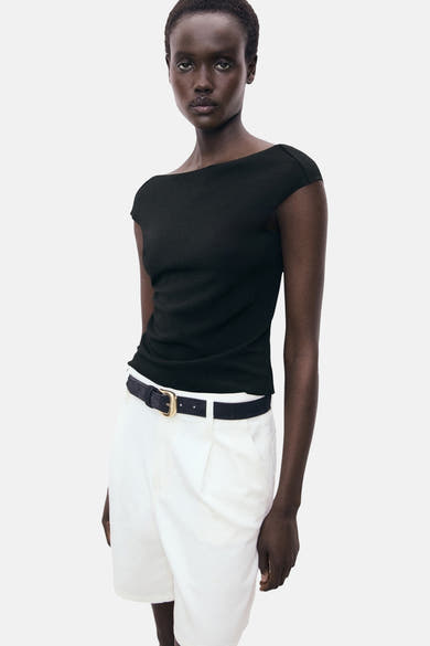 Zwart T-shirt met korte mouwen van MANGO, gedragen met een witte broek en een zwarte riem.