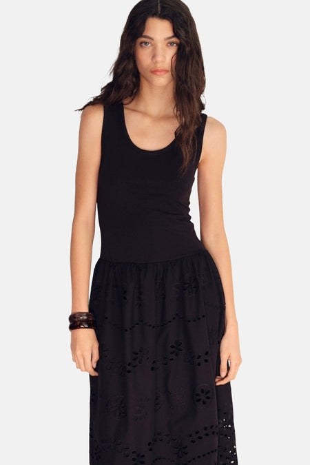 Zwarte jurk van MANGO, met geborduurde rok met bloemenpatroon en bruine armband.