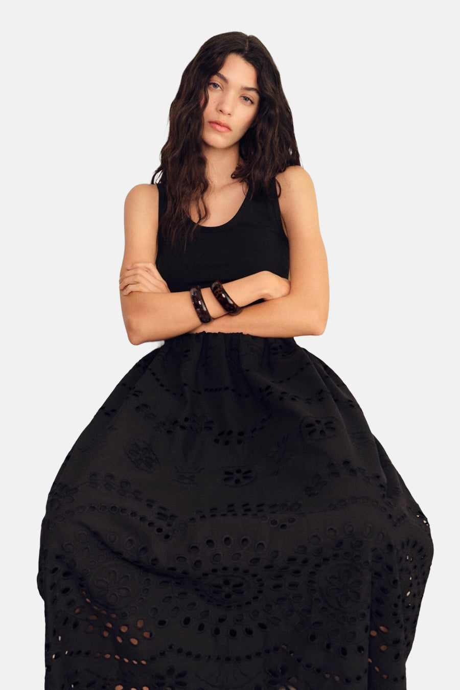 Zwarte jurk van MANGO met uitgesneden details, gedragen met een zwarte tanktop en bruine armbanden.