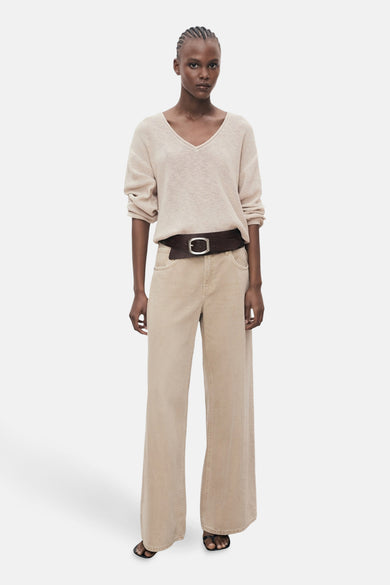 Pull à col en V beige de MANGO, porté avec une ceinture marron et un pantalon assorti.