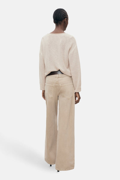 Pull à col en V beige de MANGO, porté avec un jean taille haute à jambes larges.