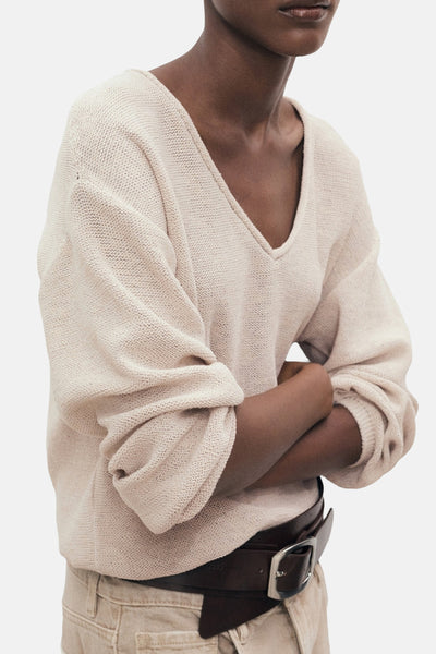 Beige V-hals trui van MANGO, met wijde lange mouwen en een bruine leren riem.