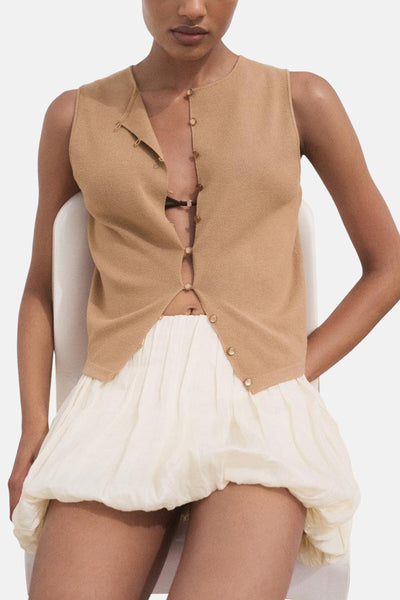 Gilet sans manches marron de MANGO, porté ouvert avec une jupe bouffante écrue.