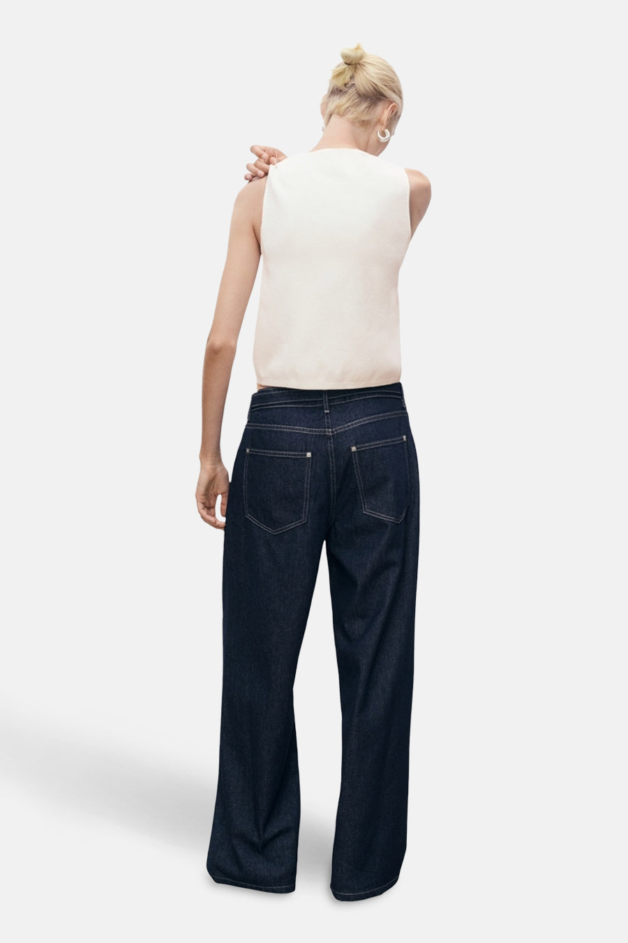 Gilet blanc de MANGO, porté avec un jean indigo ample, détail des poches arrière apparentes.