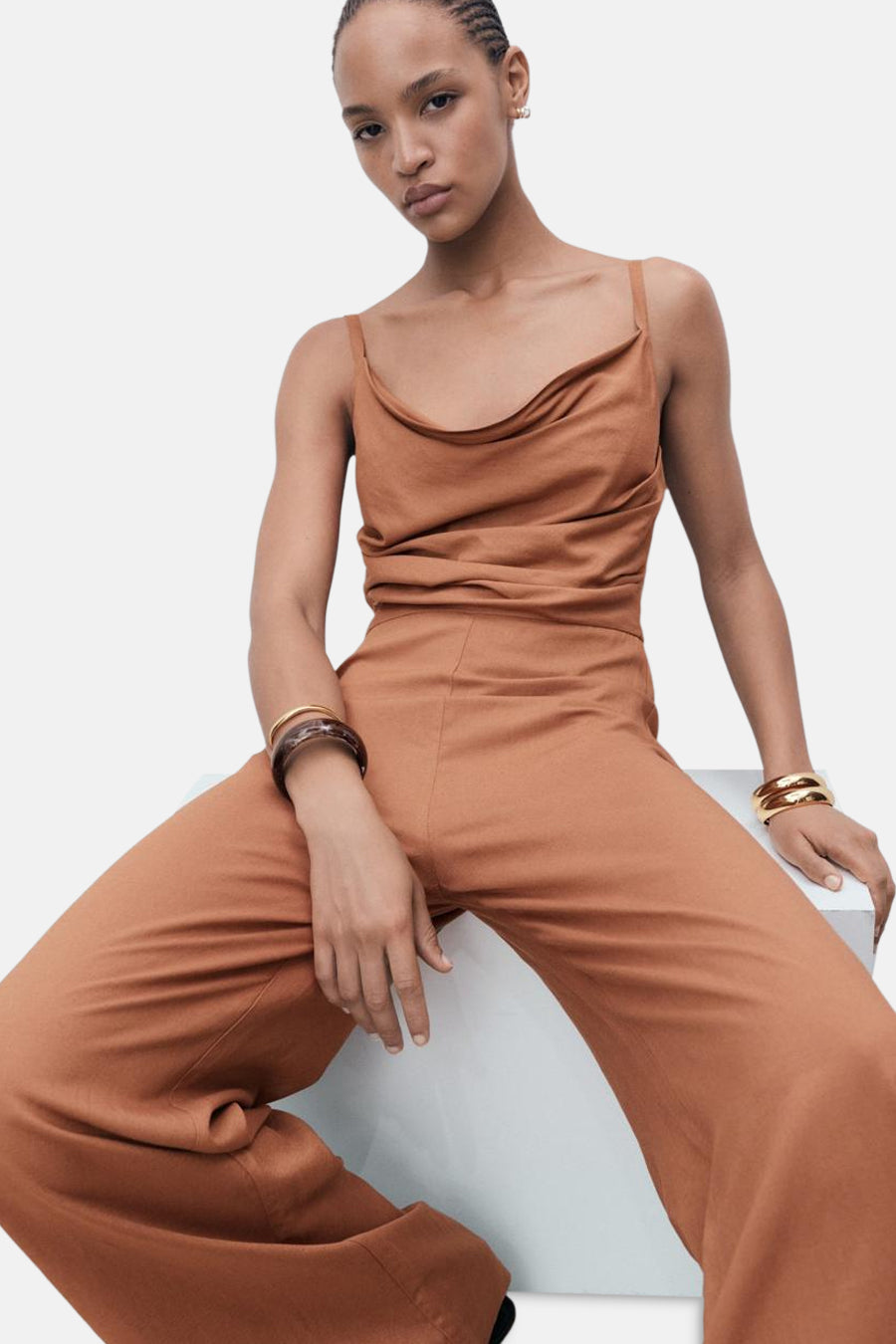 Bruin jumpsuit van MANGO, met een gedrapeerd bovenstuk en gouden accessoires.