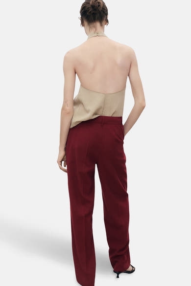 Bordeaux broek van MANGO, rechte pasvorm met zakken en afgewerkte zoom, gedragen met een beige haltertop.