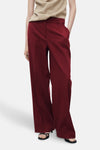Bordeaux broek van MANGO, met een losse pasvorm en wijde pijpen, gedragen met een effen beige top.