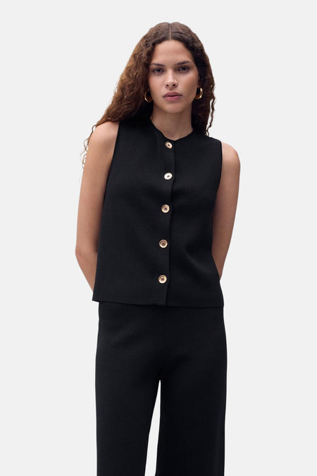 Zwart mouwloos overhemd van MANGO, met een gladde textuur, gedragen met een bijpassende zwarte broek.