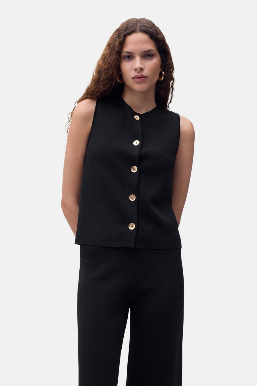 Zwart mouwloos overhemd van MANGO, met een gladde textuur, gedragen met een bijpassende zwarte broek.