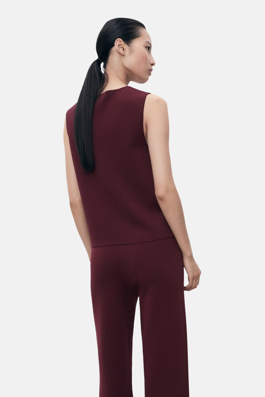 Blouse bordeaux sans manches de MANGO, vue de dos, avec un pantalon assorti.