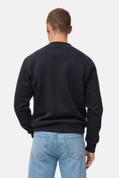 Blauwe trui van MANGO, van achteren gezien, gedragen met een casual lichte spijkerbroek.