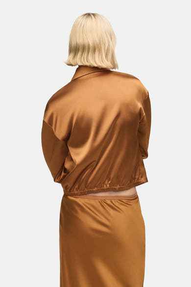 Gilet brun de MANGO, vu de dos, en tissu satiné et avec ourlet élastique à la taille.