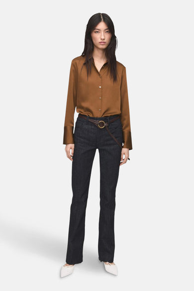 Chemise à manches longues brune de MANGO, portée avec un pantalon bleu foncé et une ceinture marron.