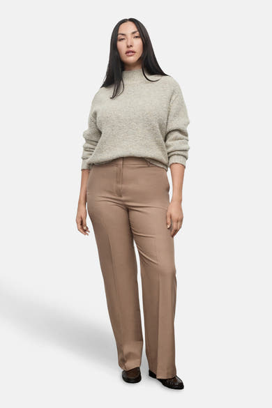 Beige broek van MANGO, rechte pasvorm en wijde pijpen, gedragen met een gemêleerde gebreide trui.