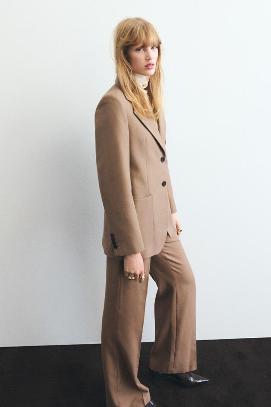 Beige broek van MANGO, rechte pasvorm met paspelzakken achter, op een effen achtergrond.