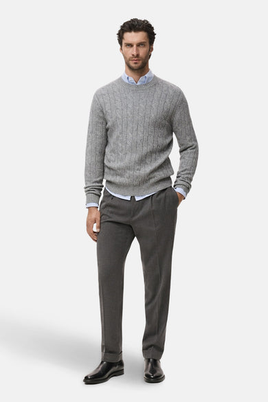 Pull gris à col rond de MANGO, porté sur une chemise bleu clair avec un pantalon et des chaussures noirs.