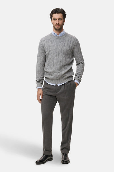 Pull gris à col rond de MANGO, porté sur une chemise bleu clair avec un pantalon et des chaussures noirs.