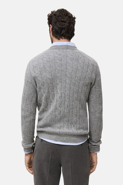 Pull à col rond gris par MANGO, motif torsadé sur un fond gris chiné, porté avec une chemise et un pantalon gris.