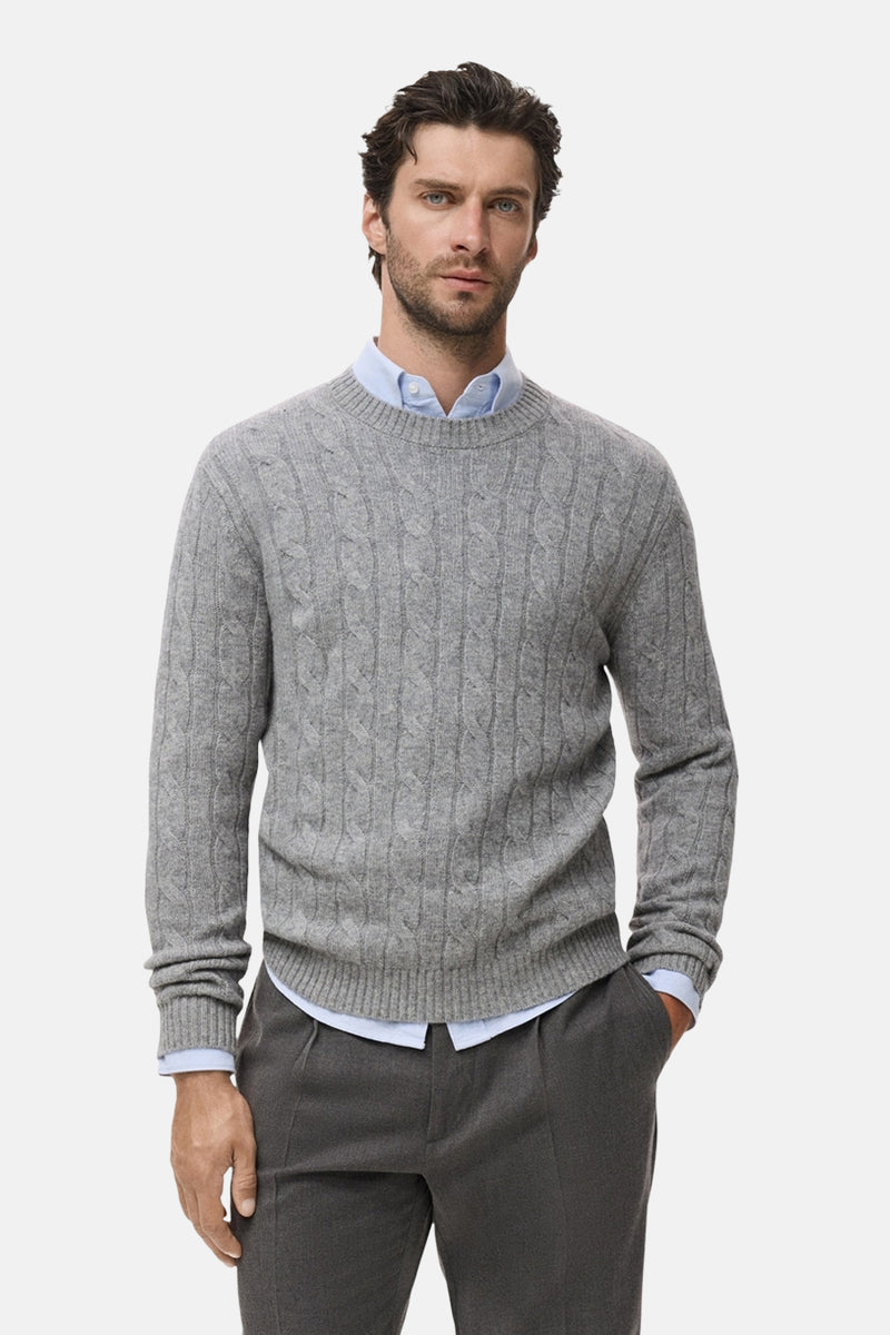 Pull à col rond gris de MANGO, avec motif torsadé, porté sur une chemise bleu clair et un pantalon gris anthracite.
