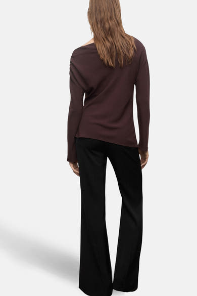 Blouse à manches longues brune de MANGO, vue de dos, portée avec un pantalon noir évasé.