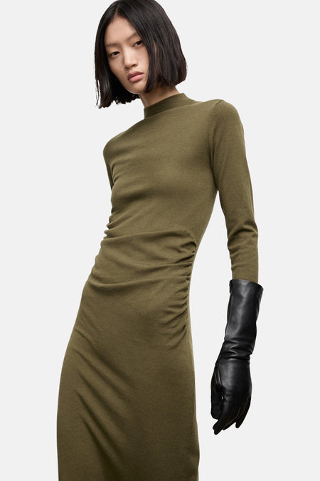 Robe kaki à manches longues de MANGO, avec effet froncé sur un côté et gant noir.
