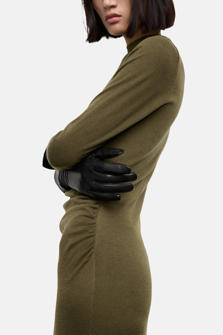 Robe kaki à manches longues de MANGO, avec des gants en cuir noir et une coupe moulante.
