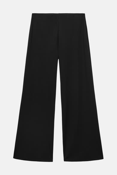 Pantalon noir ample de MANGO, coupe évasée sur fond blanc.