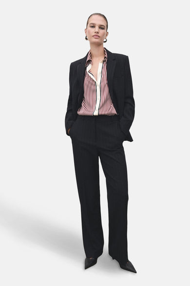 Chemise à manches longues rouge rayée de MANGO, portée avec un tailleur pantalon rayé.