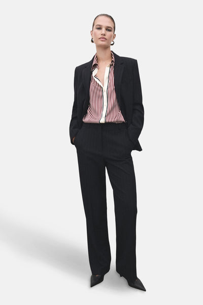 Chemise à manches longues rouge rayée de MANGO, portée avec un tailleur pantalon rayé.