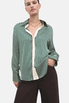 Chemise à manches longues verte rayée de MANGO, avec boutons apparents et un pantalon marron.
