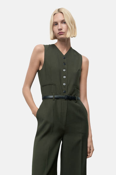 Combinaison kaki par MANGO, avec un gilet boutonné et une ceinture noire fine à la taille.