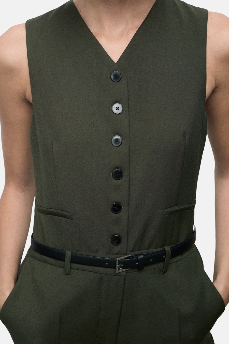 Kaki overall van MANGO, met een geknoopt vest en een dunne zwarte riem met metalen gesp.