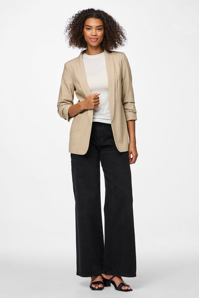 Blazer beige par PIECES, porté sur un t-shirt blanc et un jean noir large, avec des chaussures à talons.