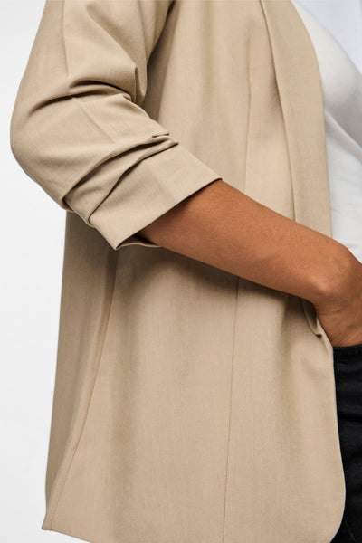 Beige blazer van PIECES®, met opgerolde mouwen en een deels zichtbare witte voering aan de binnenkant.