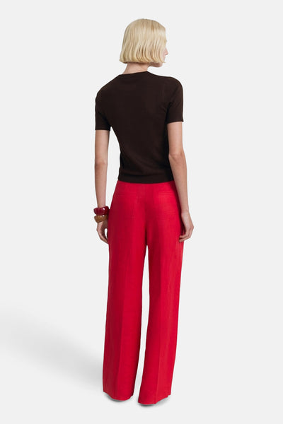 T-shirt uni à manches courtes brun de MANGO, porté avec un pantalon rouge ample et des bracelets.